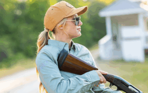 Female in orange baseball hat with sunglasses holding shotun with FalconStrike recoil pad.